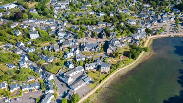Vue aérienne de l'église Notre Dame Izel Vor et du bourg de La Forêt comprenant des maisons et une partie de l'anse de La Forêt