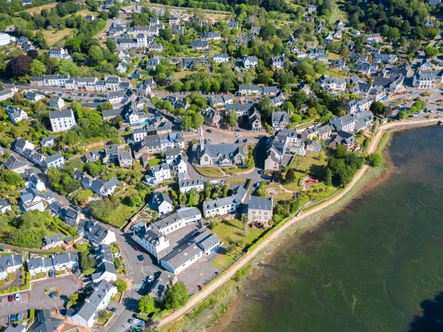 Aerial view of the church of Notre Dame Izel Vor and the market town of La Forêt, including houses and part of the La Forêt cove.