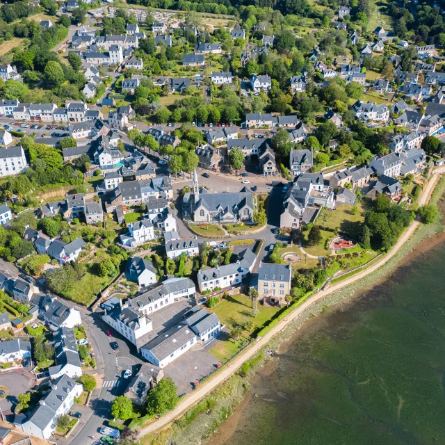 Vue aérienne de l'église Notre Dame Izel Vor et du bourg de La Forêt comprenant des maisons et une partie de l'anse de La Forêt
