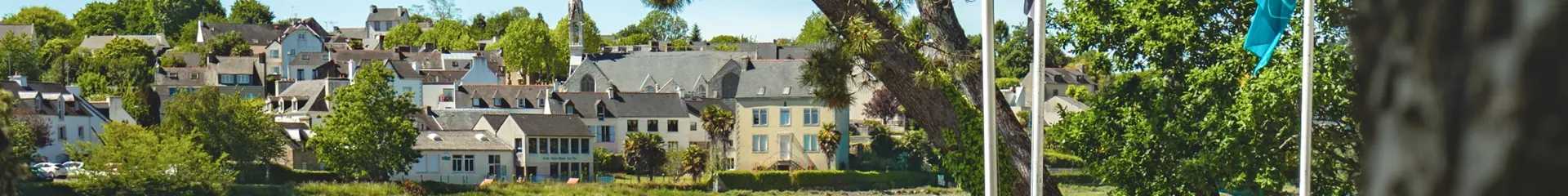 View of the La Forêt cove at high tide with the coastal path and the town of La Forêt-Fouesnant