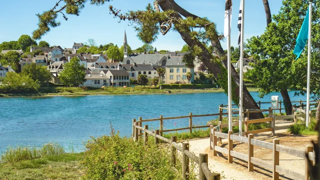 Vue de l'anse de La Forêt à marée haute avec le sentier côtier et le bourg de La Forêt-Fouesnant