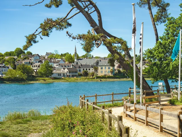 View of the La Forêt cove at high tide with the coastal path and the town of La Forêt-Fouesnant