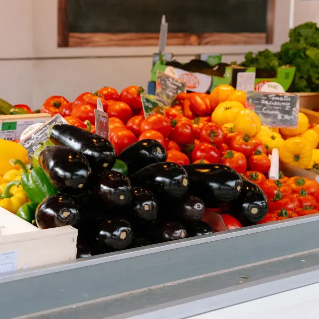 Un étale de légumes de couleur : tomate, aubergine, poivron... sur le marché