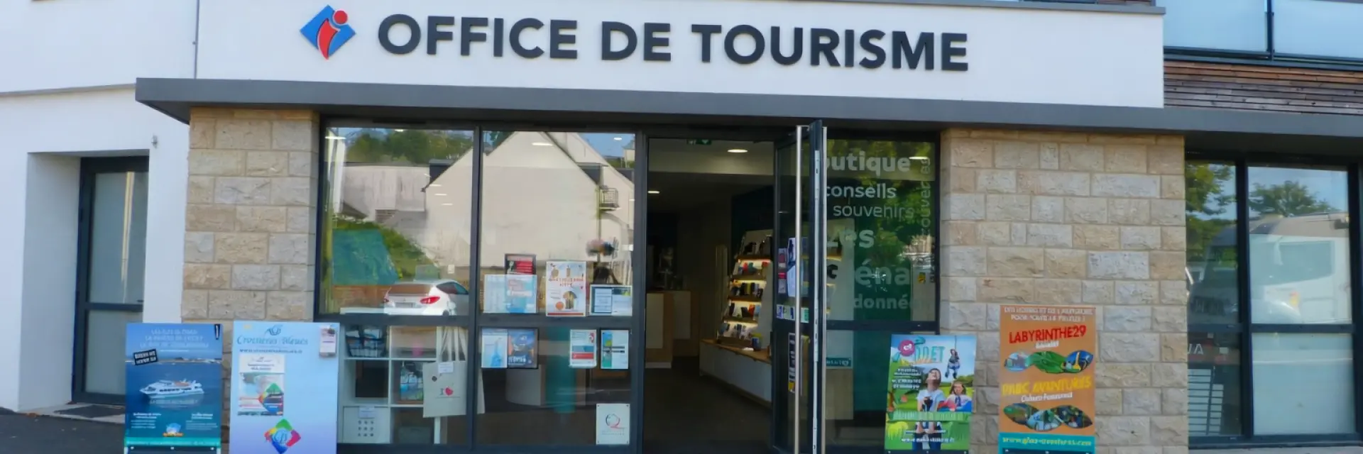 Vue de la façade de l'office de tourisme avec les baies vitrées, la porte est ouverte