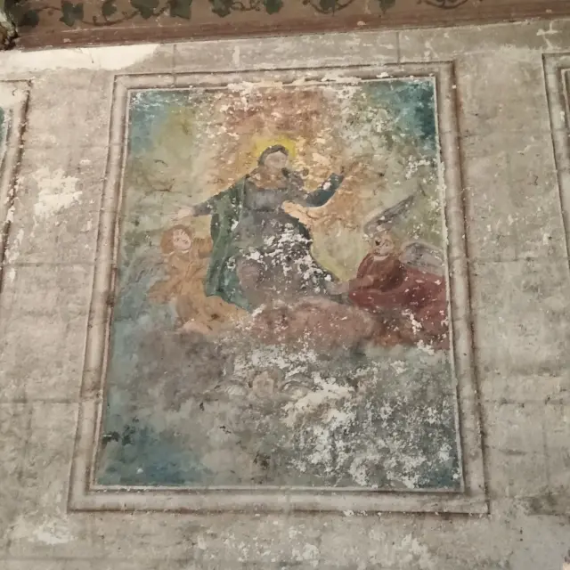 Teilweise verblasste Wandfreske mit Figuren auf einer Steinmauer